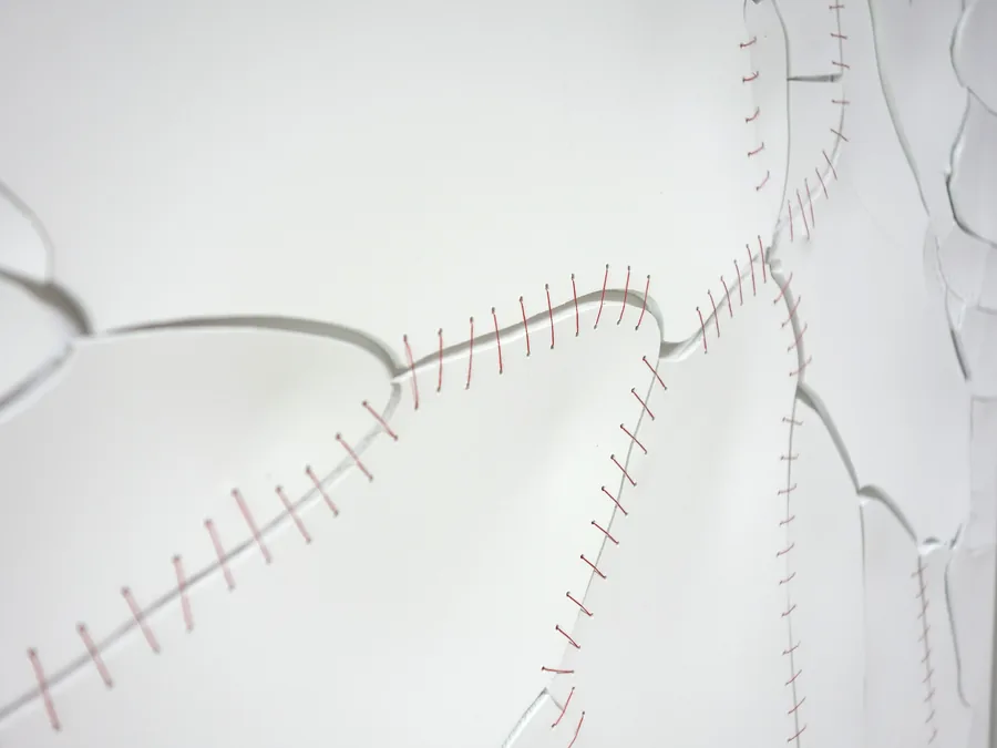 holding it together, detail, the cracks stitched with red thread